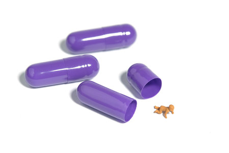Miniature tiny people toy figure photography. A newborn baby crawling out from inside of purple medicine pill tablet. Isolated on white background. Image photoの写真素材