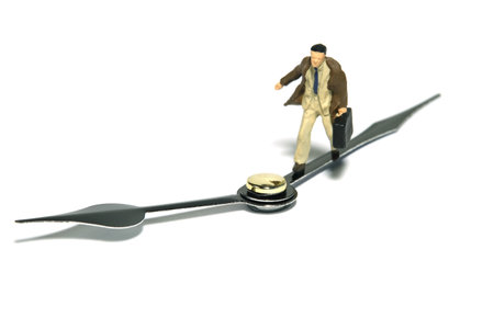 Miniature tiny people toy figure photography. A businessman running above black clockwise carrying briefcase. Isolated on white background. Image photoの写真素材