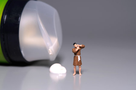 Miniature tiny people toy figure photography. A man getting shaving his beard standing beside shaving soap and cream on grey background. Image photoの写真素材