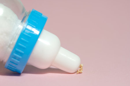 Miniature tiny people toy figure photography. A boy toddler infant drinking a milk of bottle. Isolated on pink background. Image photoの写真素材