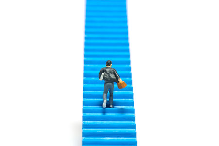 Miniature people toy figure photography. A boy pupil student running on staircase. Isolated on a...