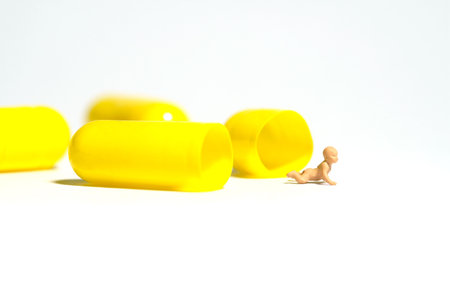 Miniature tiny people toy figure photography. A newborn baby crawling out from inside of yellow medicine pill tablet. Isolated on white background. Image photoの写真素材