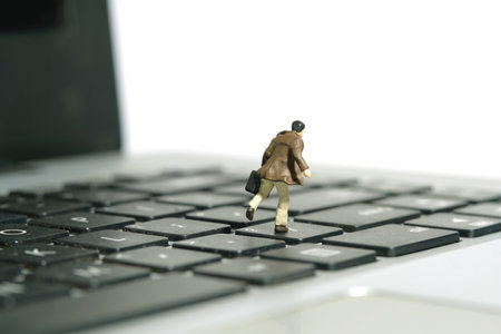Miniature tiny people toy figure photography. A businessman running above keyboard notebook laptop carrying briefcase. Isolated on white background. Image photoの写真素材