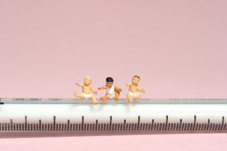 Miniature tiny people toy figure photography. Group of boy toddler infant baby seat above needle syringe whimpering. Isolated on pink background. Image photoの写真素材