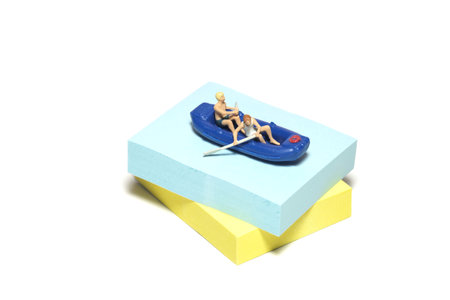 Creative miniature people toy figure photography. Sticky notes installation. Two boys rowing a...