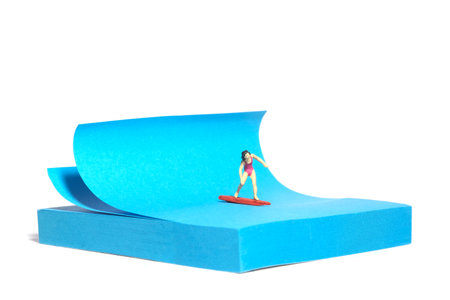 Creative miniature people toy figure photography. Sticky notes installation. A girl surfer riding big waves on surfing board. Isolated on white background. Image photoの写真素材
