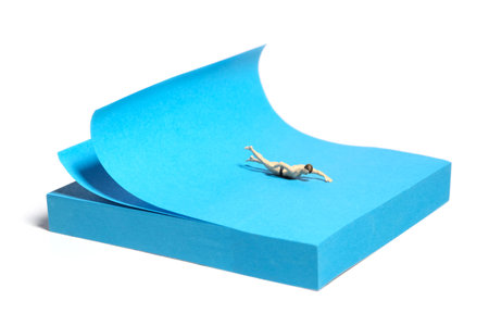 Creative miniature people toy figure photography. Sticky notes installation. A men swimming on the ocean with big waves. Isolated on white background. Image photoの写真素材