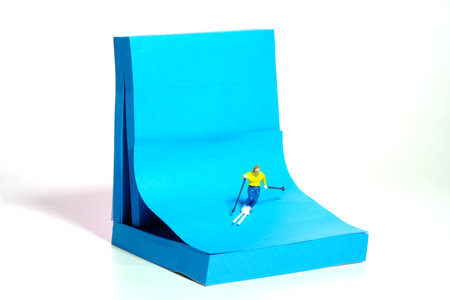 Creative miniature people toy figure photography. Winter sport sticky notes installation. A male downhill ski racer slides down from the top of the hill. Image photoの写真素材