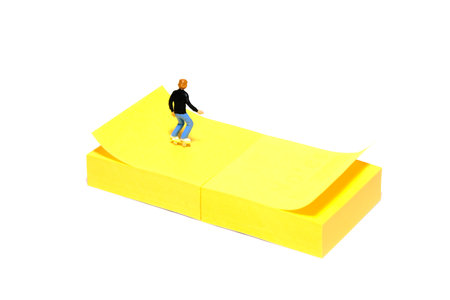 Creative miniature people toy figure photography. Sticky notes installation. A boy roller skater playing at skate park. Isolated on white background. Image photoの写真素材