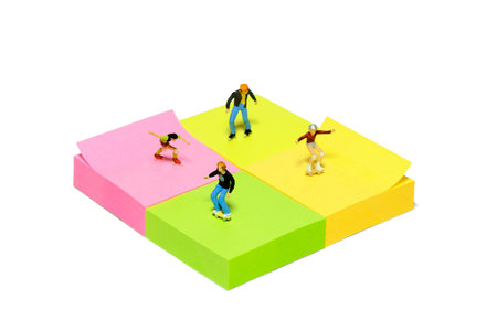 Creative miniature people toy figure photography. Sticky notes installation. Kids playing roller skater at skate park. Isolated on white background. Image photoの写真素材