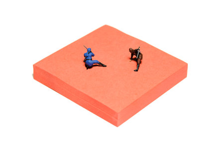 Creative miniature people toy figure photography. Sticky notes installation. Two ninja fighting on red mat arena. Image photoの写真素材