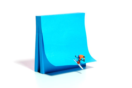 Creative miniature people toy figure photography. Winter sport sticky notes installation. A male downhill ski racer slides down from the top of the hill. Image photoの写真素材