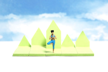 Creative miniature people toy figure photography. Sticky notes installation. A woman doing outdoor yoga with mountain hill and sky background. Image photoの写真素材