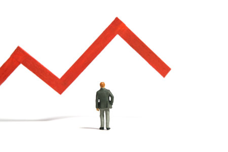 Miniature tiny people toy figure photography. Investment failure and loss concept. A businessman standing in front of red bar declining graph. Isolated on a white background. Image photoの写真素材