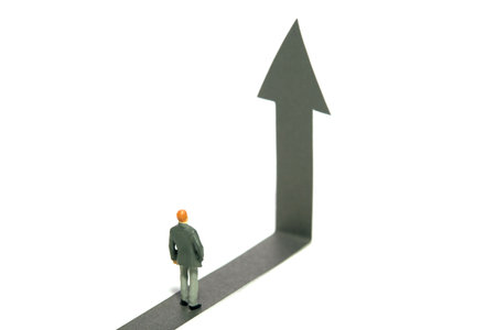 Miniature tiny people toy figure photography. Business strategy and opportunity concept. A businessman looking on road climbing up arrow. Isolated on a white background. Image photoの写真素材