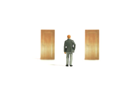Miniature tiny people toy figure photography. Businessman standing in front of two door, thinking which one to choose different to goal success opportunity. Image photoの写真素材