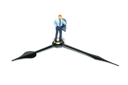 Miniature tiny people toy figure photography. A businessman standing above clockwise. Isolated on white background. Image photoの写真素材