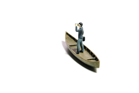 Miniature tiny people toy figure photography. Business opportunity concept illustration. Businessman using binocular telescope sail with boat. Isolated on a white background. Image photoの写真素材