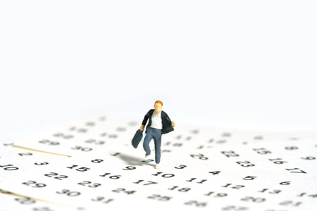 Miniature people toy figure photography. A boy pupil student running above calendar. Isolated on a white background. Image photoの写真素材