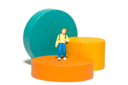 Miniature people toy figure photography. A boy kindergarten student playing Montessori wooden block....
