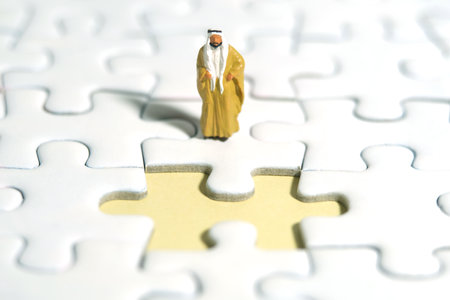 Miniature people toy figure photography. A Sultan wearing yellow Bisht (king cloak) standing in front of missing piece puzzle jigsaw. Image photoの写真素材
