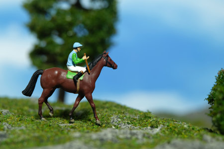 Miniature people toy figure photography. A jockey man riding horse at mountain hill for training. Image photoの写真素材