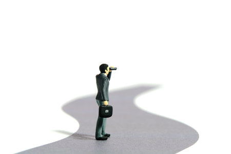 Miniature tiny people toy figure photography. Business road concept illustration. Businessmen using binocular walking on winding road. Isolated on a white background. Image photoの写真素材