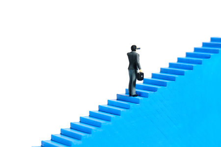 Miniature tiny people toys photography. Businessman walking up the stair. Isolated on white background. Image photoの写真素材