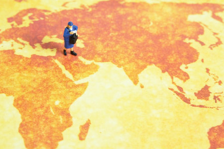 Miniature people toys conceptual photography. Global, international delivery service. Postman, courier standing above map.の写真素材