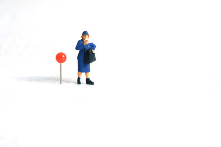 Miniature people toys conceptual photography. Courier pinpoint location pickup package delivery service. Postman with red push pin, isolated white background.の写真素材