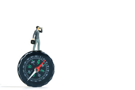 Businessmen standing using binoculars above black compass. Miniature tiny people toys photography. isolated on white background.の写真素材
