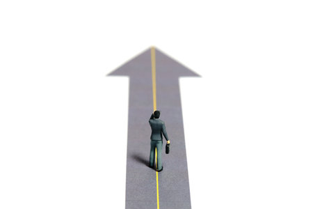 Miniature tiny people toy figure photography. Business opportunity concept illustration. Businessmen walking on a road with arrow. Isolated on a white background. Image photoの写真素材