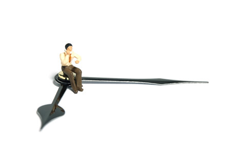 Miniature tiny people toy figure photography. Working hour concept. A businessmen make a phone call, seat above clockwise. Isolated on a white background. Image photoの写真素材