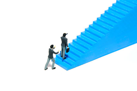 Miniature tiny people toys photography. Business support, teamwork. Businessman start to walk the blue stairway. Isolated on a white background. Image photoの写真素材