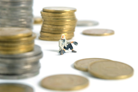 Miniature people toy figure photography. Bankruptcy concepts. A beggar man with no money seat in the middle of coin stack money. Isolated on white background. Image photoの写真素材
