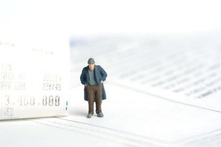 Miniature people toy figure photography. Trouble paying bills concepts. A sad man with no money standing beside receipt of payment. Isolated on white background. Image photoの写真素材