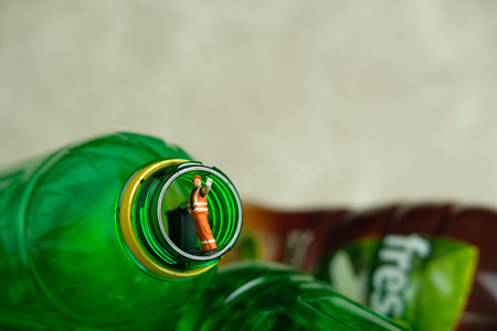 Miniature people toy figure photography. Cleaning worker with trash bin walking between drink bottle plastic. Image photoの写真素材