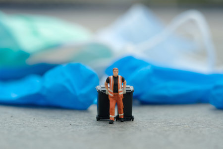 Miniature people toy figure photography. Cleaning worker with trash bin walking between used rubber latex gloves on the road. Image photoの写真素材