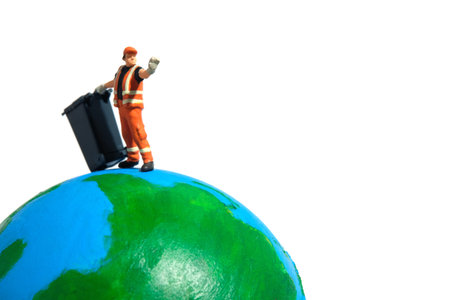 Cleaning worker with trash bin standing above earth globe. Global waste concept. Miniature people figure photographyの写真素材
