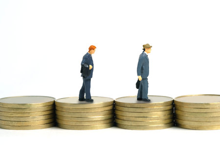 Miniature people toy figure photography. Businessman walking above flat coin pile. Isolated on white background. Image photoの写真素材