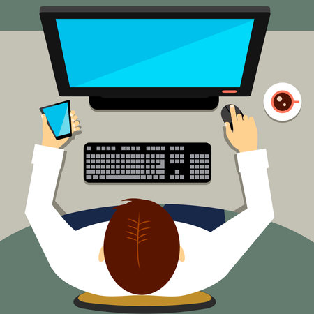 High-angle of a man sitting in the office and working on a desktop computer with blank screen while holding a smart mobile phone with the left handのイラスト素材