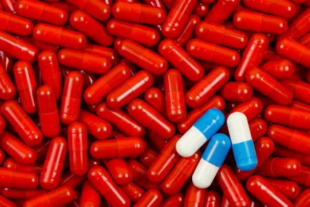 Blue and white pills on background of red pills