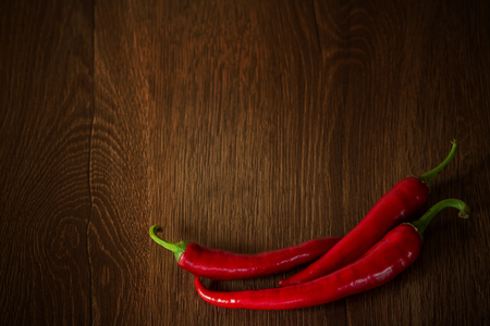 Red peppers on the brown table. Hot peppers on wooden background. Chilli peppers background with copy spaceの写真素材