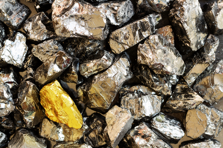 Golden bar on background of raw coal nuggets close-upの写真素材