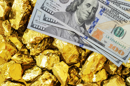 One hundred dollar banknotes on gold mine close up. Mining industry concept with dollars and gold
