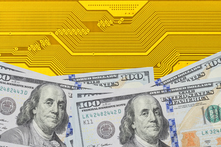 Conceptual image of power in digital and financial industry. Stack of dollar bills on electronic circuit board close up.の写真素材
