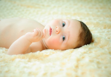 Beautiful baby boy is lying in a bed.