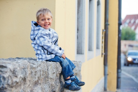 little boy sits near the old houseの写真素材