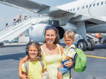 Young mother with two kids in front of airplaneの写真素材