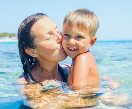 Portrait of young boy swimming with his mother in the transparent seaの写真素材